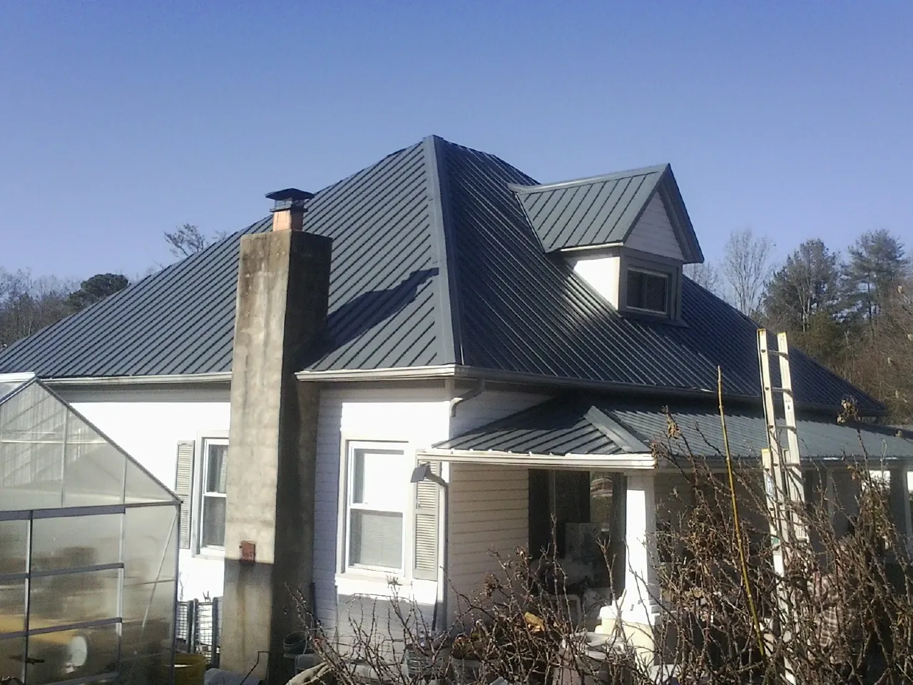 Dark blue standing seam metal roof on a white farmhouse with dormer — Slate & Tile Roof Repair by Roofing Brothers in Newark Valley