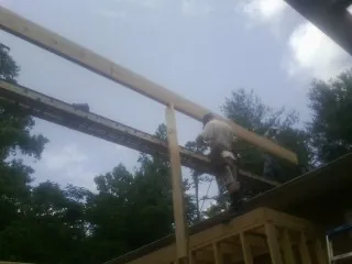 Carpenter setting a ridge beam over a new addition frame — Ice Dam Removal by Roofing Brothers in Newark Valley