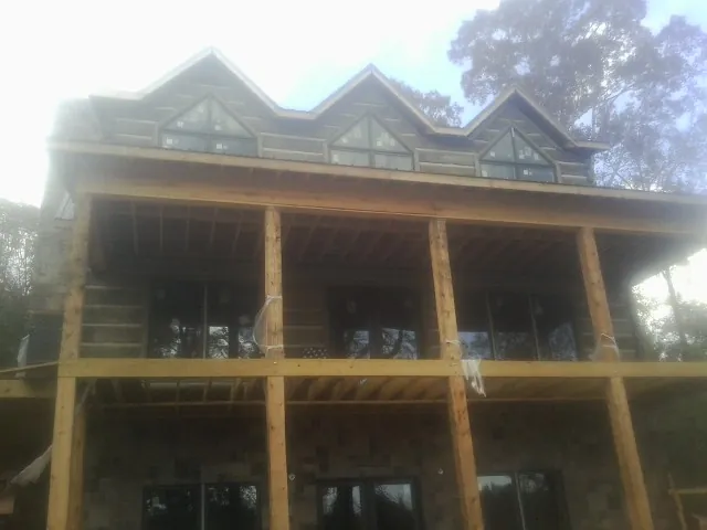 Dormers and porch framing on a large log home under construction — Roof Coating work by our crew in Newark Valley
