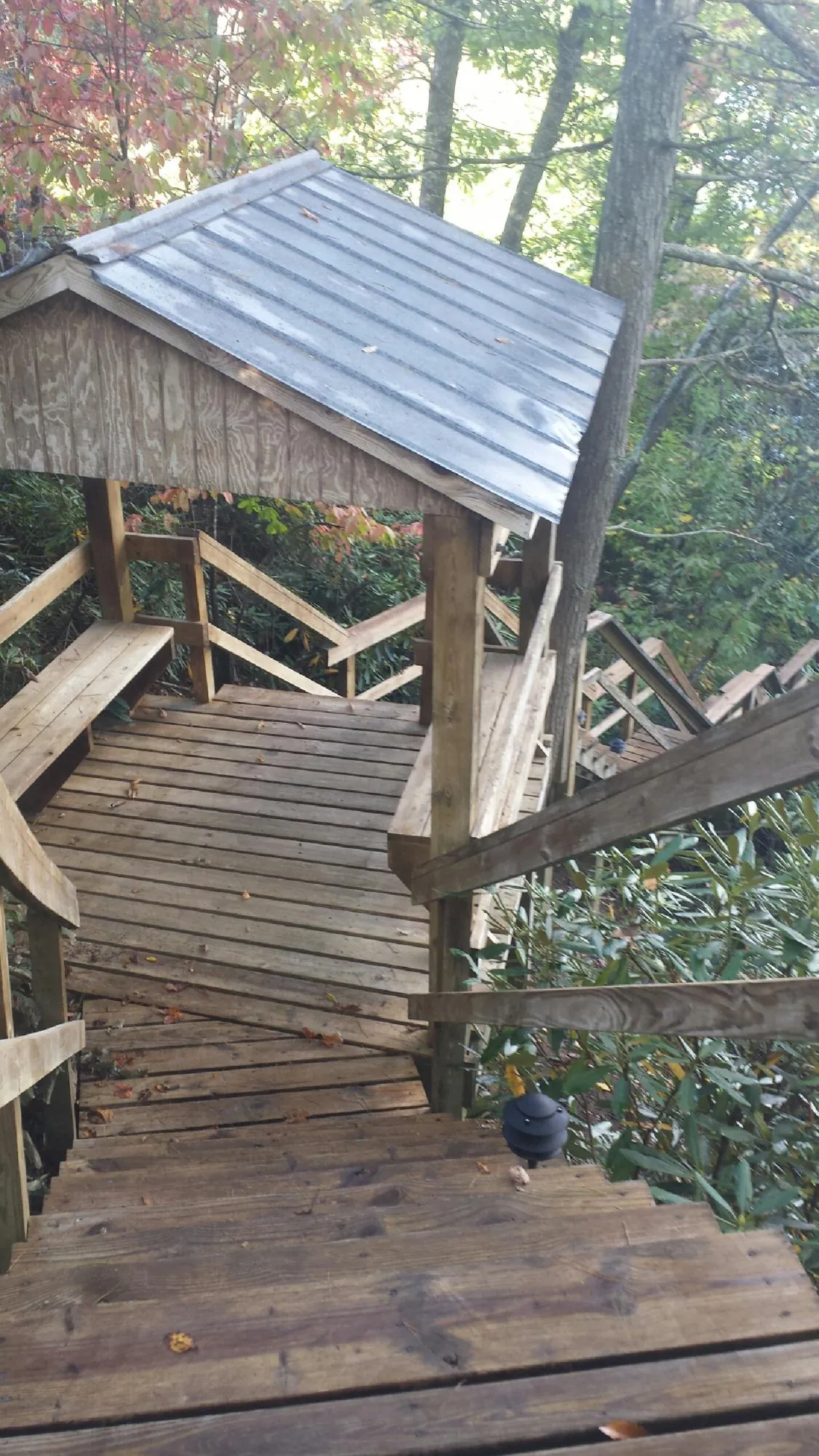 Metal roofed shelter over wooden steps on a wooded walkway — Skylight Repair & Installation work by our crew in Newark Valley