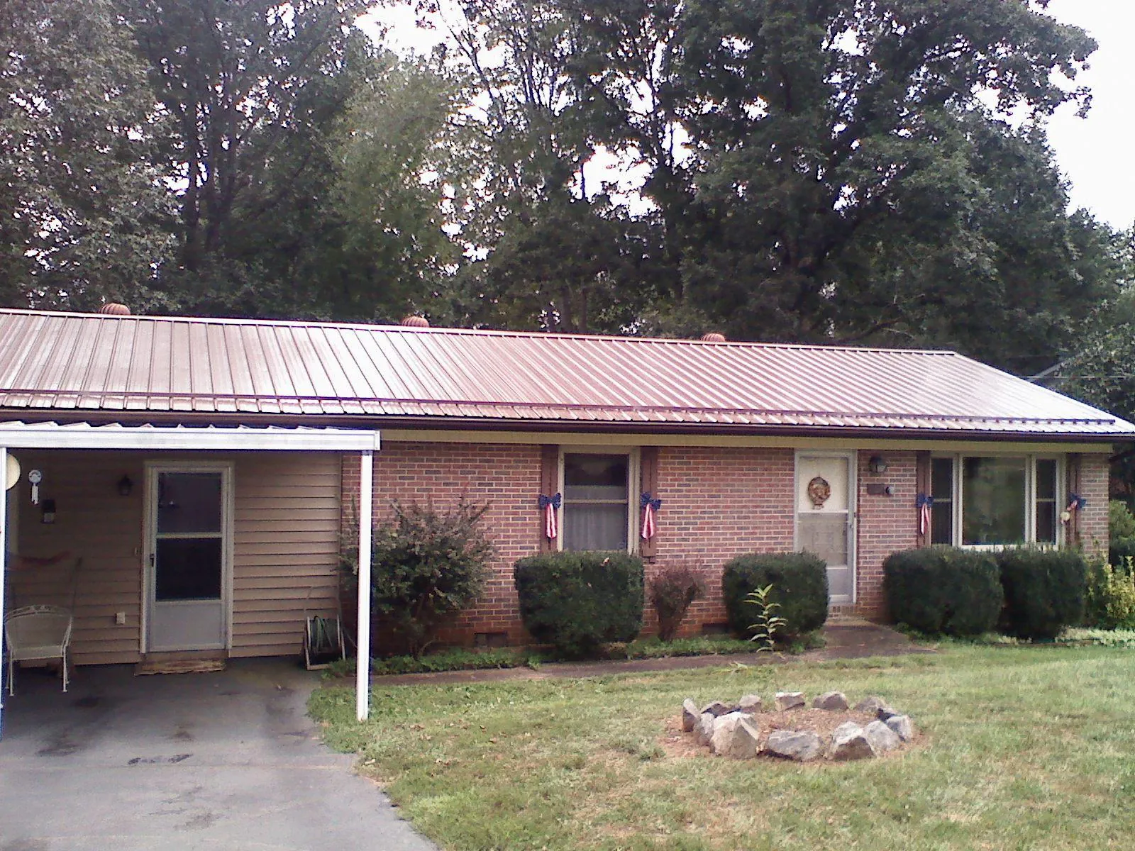 Bronze metal roof and carport on a brick ranch home — Roof Repair work by our crew in Newark Valley