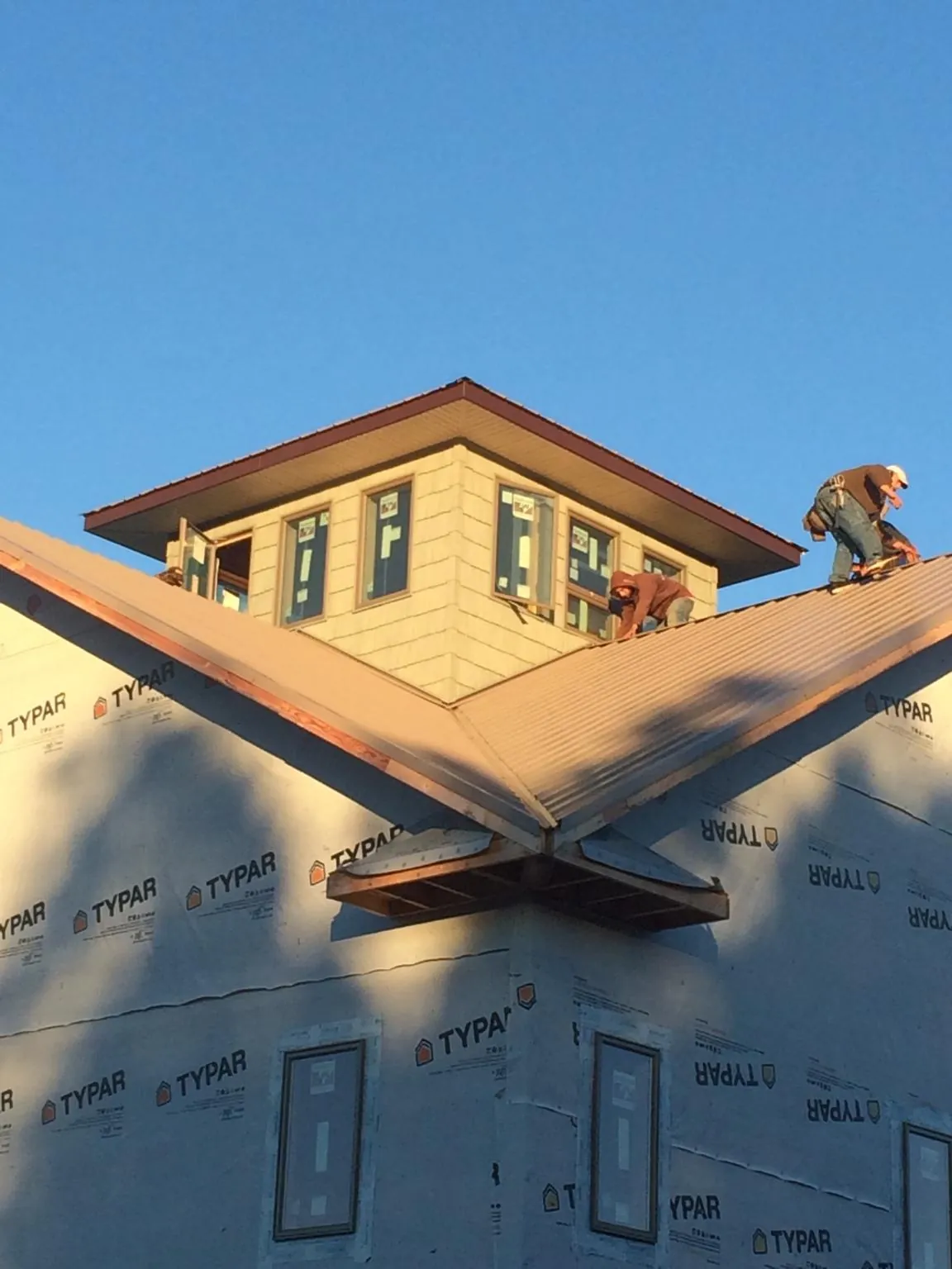 Roofers working around a rooftop cupola on a new metal roof at sunset — Roof Waterproofing in Newark Valley by Roofing Brothers